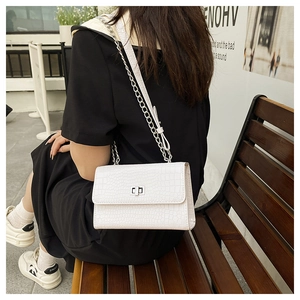 Close-up of white crocodile pattern shoulder bag with silver metal buckle and chain strap
