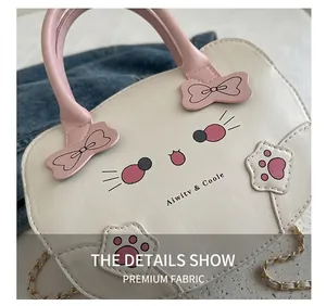 Detalle del bolso de gato blanco con lazos rosa y letras de la marca grabadas