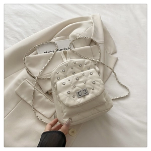 Détail du mini sac à dos beige matelassé avec strass brillants et chaîne argentée