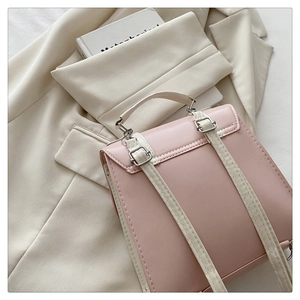 Detail of adjustable straps and metal buckles on a pink and beige fashion backpack