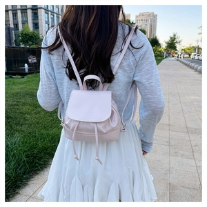 Close-up of small pink PU leather backpack with drawstring closure and mim logo embossing