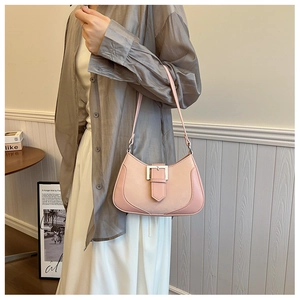 Close-up of a pink crescent shoulder bag with a silver metal buckle and leather strap
