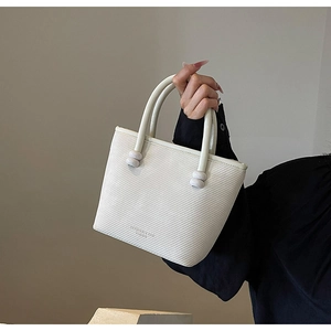 Détail du sac cabas blanc texturé avec poignée ronde et logo de marque en relief
