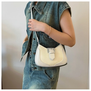 Detail view of cream crescent bag with metal buckle on model in denim outfit