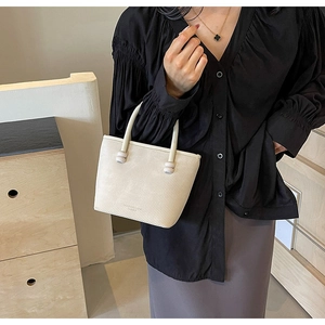 Détail du sac cabas blanc cassé avec texture sergée et garniture boule sur la sangle