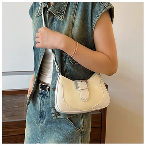 Minimalist beige leather crescent underarm bag with silver buckle worn by a model