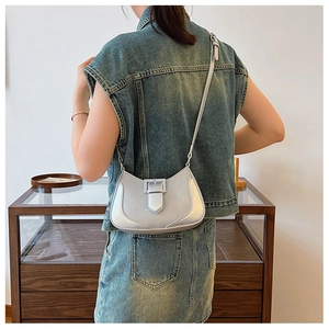 Silver-blue metallic crescent shoulder bag shown on model with stylish belt buckle detail
