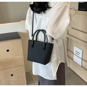 Détail du sac bandoulière noir avec poignées cylindriques et grain diagonal élégant