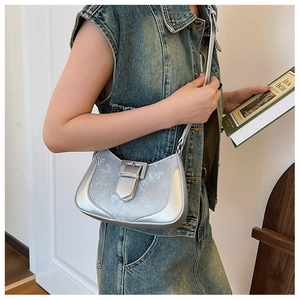 Detail view of a stylish silver metallic crescent bag paired with a denim vest.