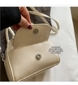 Detail of minimalist cream leather bag showing the convenient hidden magnetic closure
