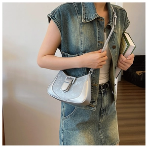 Close-up of a silver crescent shoulder bag with metallic texture and buckle detail