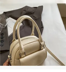 Detail of cream white shell-shaped handbag with pleated texture and silver hardware