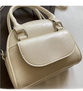 Detail of cream shell bag featuring natural leather texture and silver hardware accents