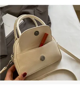 Detail view showing front pocket of cream crossbody bag with a lipstick inside