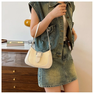 Detail of a creamy white crescent underarm bag with silver buckle on a retro outfit