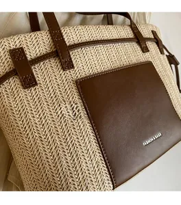 Detail of woven straw tote bag featuring brown faux leather pocket and fashion text