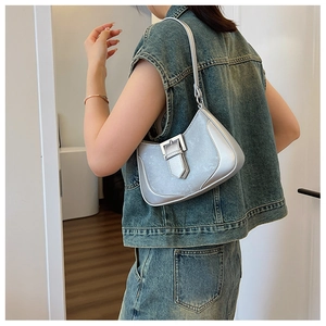 Silver metallic crescent underarm bag with decorative buckle shown on a model shoulder