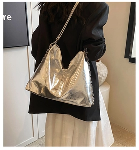 Detail of silver metallic Hobo bag with chain strap shown on a model in modern interior