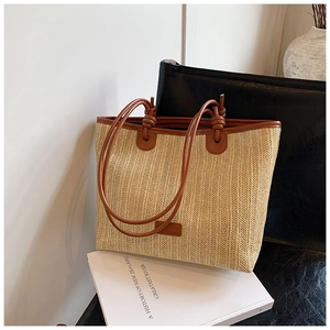Detail of minimalist straw tote bag featuring vertical weave texture and brown leather knots
