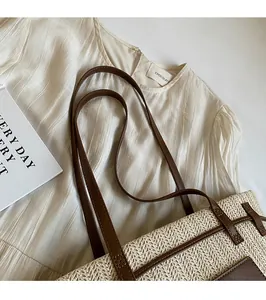 Detail of woven straw tote bag featuring premium brown leather straps and texture