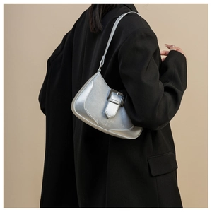 Close-up of a metallic silver crescent bag on a black blazer with matte finish detail