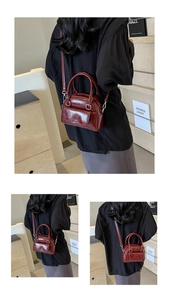 Detail view of a wine red glossy patent leather shell bag with silver metal hardware