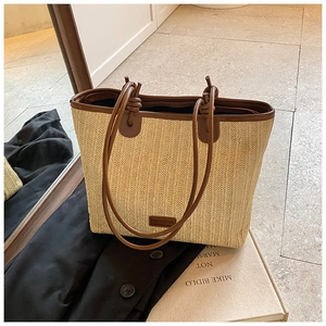 Close-up of large woven straw tote with dark brown leather trim and stylish logo detail