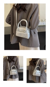 Detail of silver metallic top handle bag showing textured leather and front flap pocket