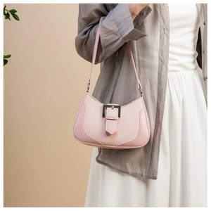 Detail of pink crescent bag with silver square buckle worn by a model on light background