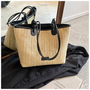 Detail of hand-woven straw tote bag with black leather trim and elegant knotted straps