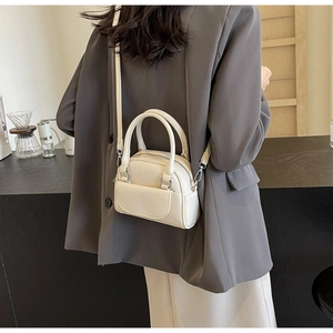 Details einer cremefarbenen Muscheltasche aus Leder mit silbernen Metallbeschlägen
