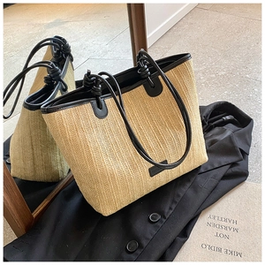 Macro detail of straw woven tote bag featuring black leather trim and knot handle design