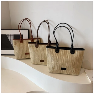 Detailed view of handmade straw bags featuring striped weave and dual leather handles