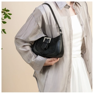 Detail of black crescent shoulder bag featuring matte leather and suede patchwork design