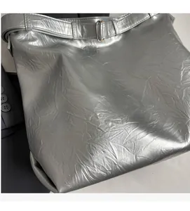 Close-up of silver bucket bag with soft pleated metallic texture and adjustable strap