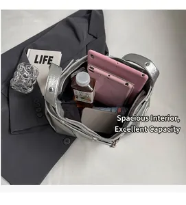 Interior view showing large storage capacity of the silver pleated tote bag on a grey blazer