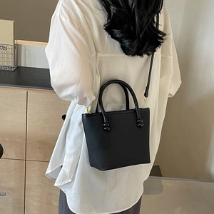 Sac fourre-tout noir minimaliste avec texture porté par un mannequin dans un intérieur