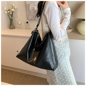 Detail of a black leather hobo bag with a silver chain strap for casual commuting