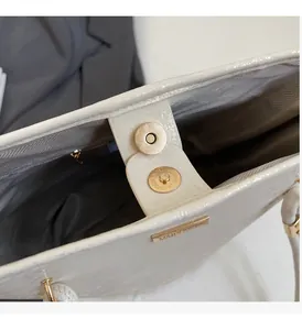 Dettaglio della borsa in pelle bianca con chiusura magnetica dorata e logo in metallo