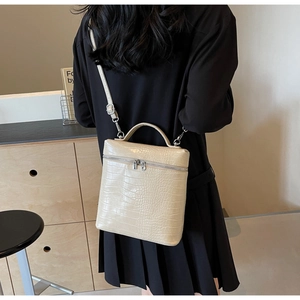 Dettaglio di una borsa beige con stampa coccodrillo portata a spalla in una stanza moderna