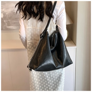 Detail of black large capacity tote bag with oil-wax texture and metal chain accents