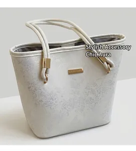 Dettaglio della borsa a secchiello effetto marmo bianco con placca dorata