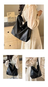 Detail of large black tote bag with wrinkled texture and wide shoulder strap
