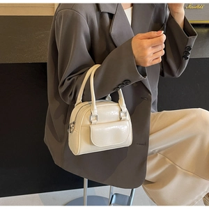 Schicke cremefarbene Mini-Bowling-Tasche am Modell mit Doppelgriffen und Silber-Zipper