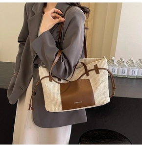 Detail of woven tote bag with brown leather straps and fashion branding on side