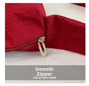 Detail shot of the smooth silver zipper and white U-shaped puller on red nylon bag