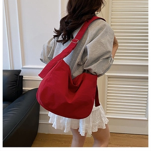 Detailed view of large bright red canvas crossbody bag with adjustable wide strap on model