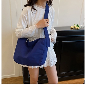 Detail of dark blue canvas crossbody bag showing high-density fabric texture and strap