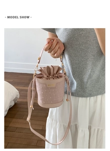 Detail of light pink bucket bag featuring drawstring closure and round top handle