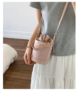 Detail of pale pink bucket bag showing golden hardware and drawstring inner pouch